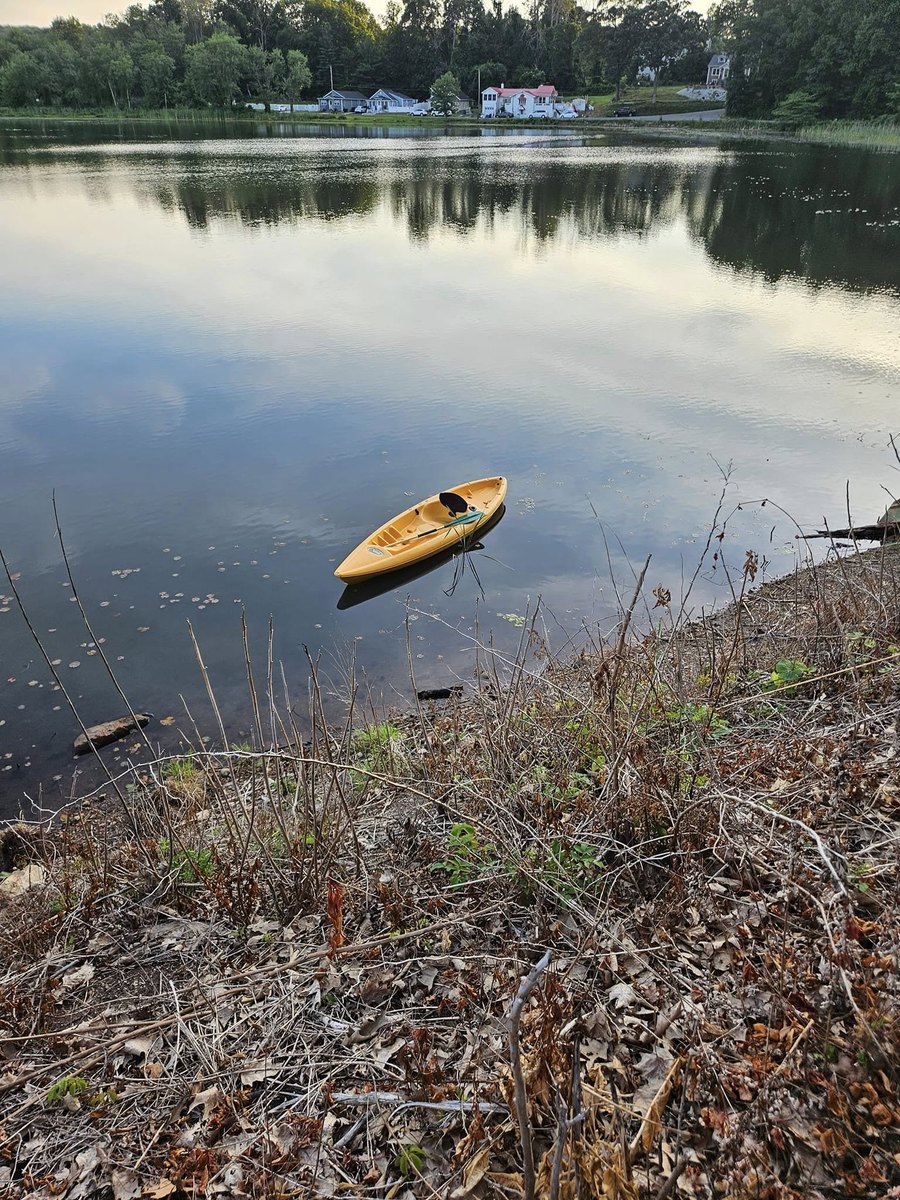 Yellow kayak floating near the wooded shoreline of Sparta Lake