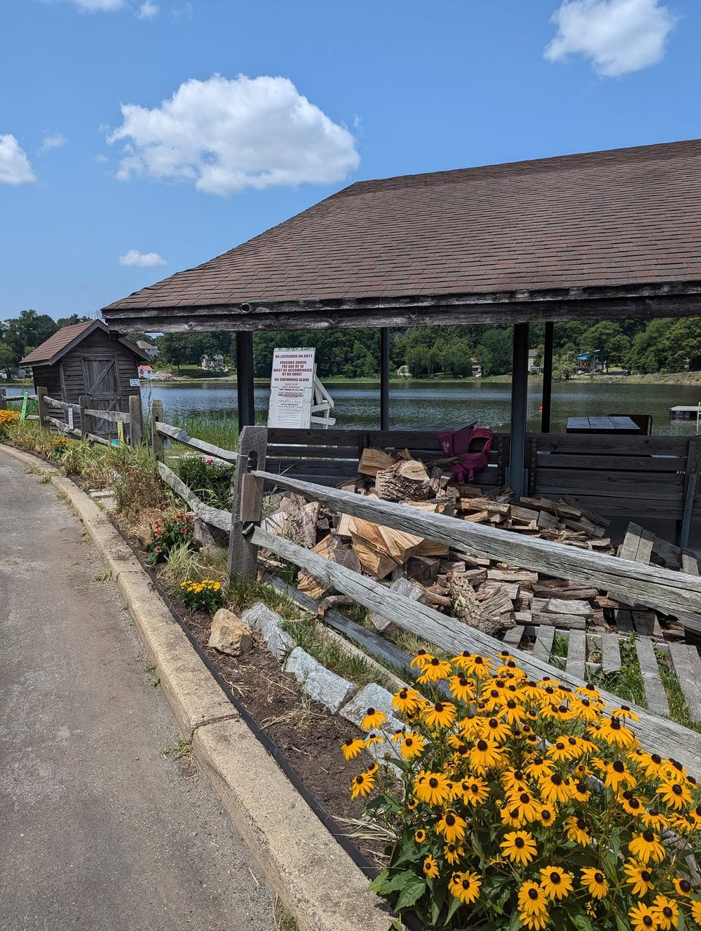 Flowers and stacked firewood beside the Sparta Lake pavilion